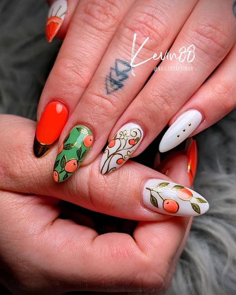 Hand-painted orange fruit nail art with green leaves and a gold French tip, done at 88 Nails in Lewisville